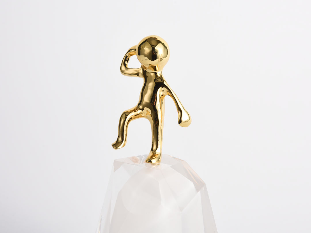 Златен метален човек върху акрилна скулптура за фигурка